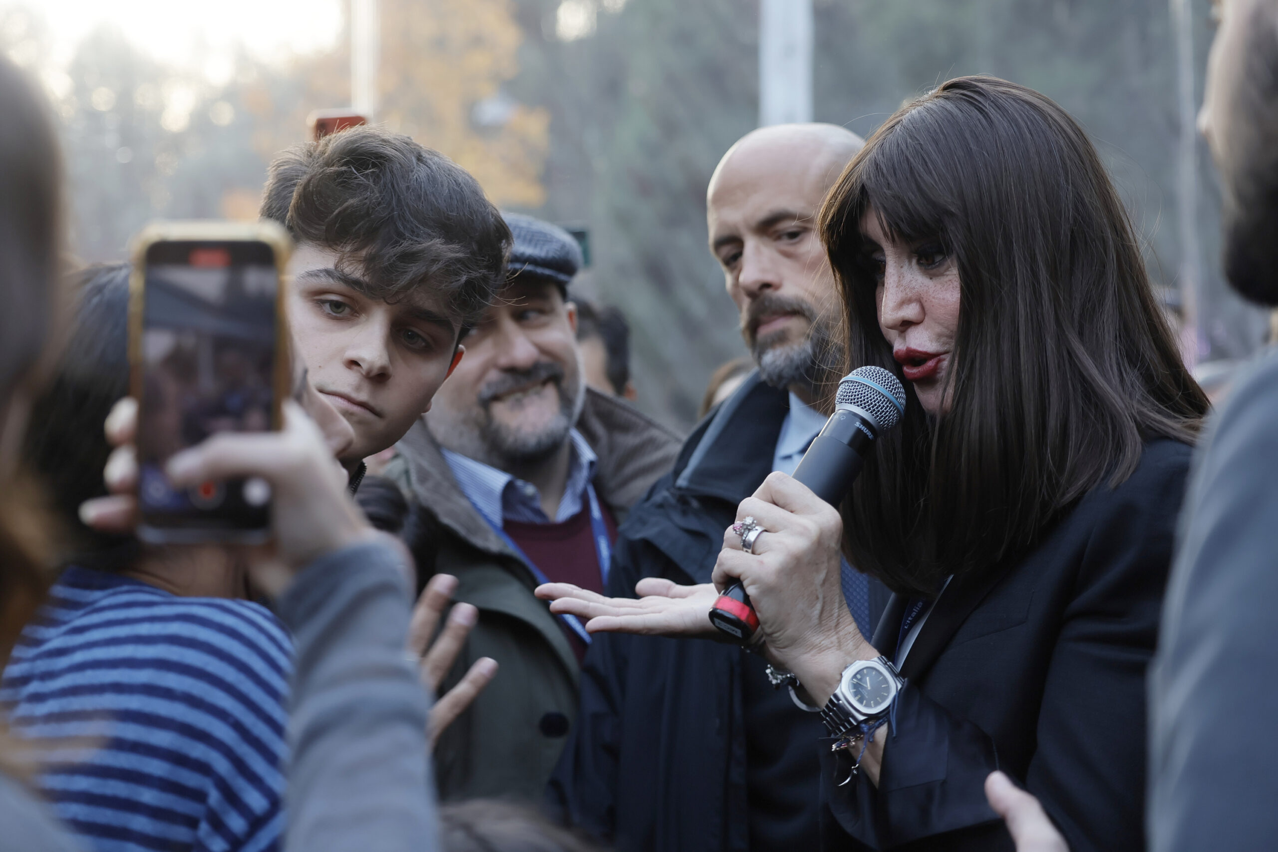 La ministra Anna Maria Bernini parla al microfono mentre studenti dell’UDU la contestano durante un panel sull’università ad Atreju 2025, a Roma.
